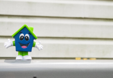 Happy House mascot toy in front of home