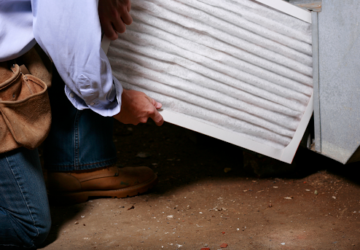 An HVAC technician changing a furnace's air filter in an Erlanger, KY, home.