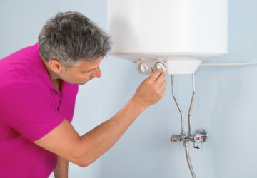 A man adjusting the settings on a water heater.