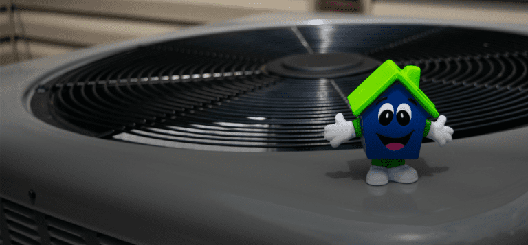 Happy House trinket standing on top of outdoor central AC unit installed outside of Cincinnati, OH home.