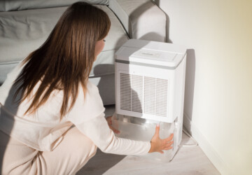 Woman checking water collected in dehumidifier.