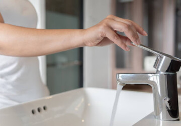 A woman turning on a faucet.