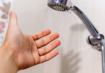 A hand testing the temperature of shower water.