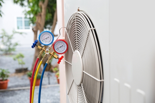 Close-up of HVAC installation with pressure gauges connected to an air conditioning unit.