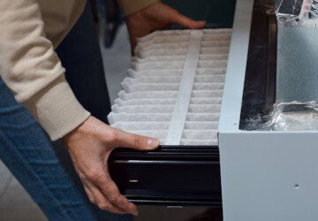 A homeowner replacing a furnace air filter.