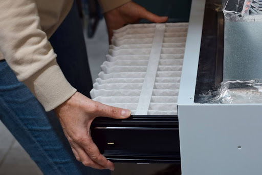 A homeowner replacing a furnace air filter.