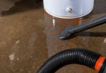 A wet-dry vacuum being used to clean up water from a leaking residential water heater.