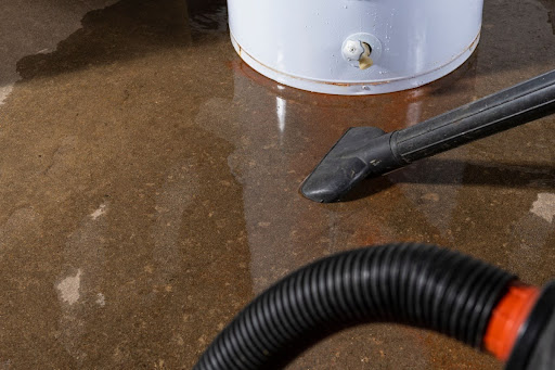 A wet-dry vacuum being used to clean up water from a leaking residential water heater.