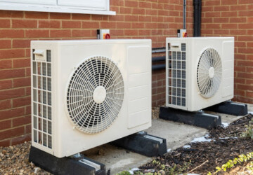 Two heat pumps installed outside on concrete slabs.